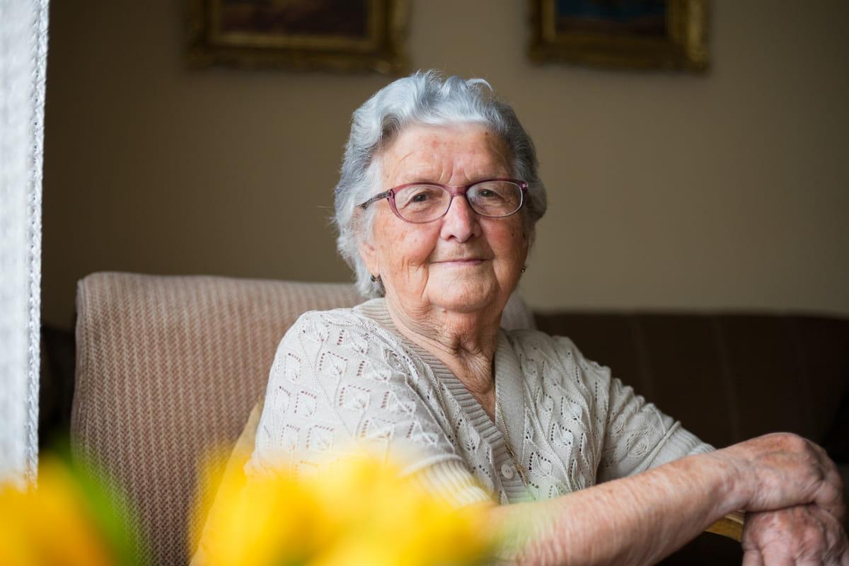 Senior woman smiling with flowers in foreground